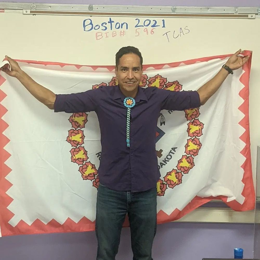 man holding rosebud tribe flag